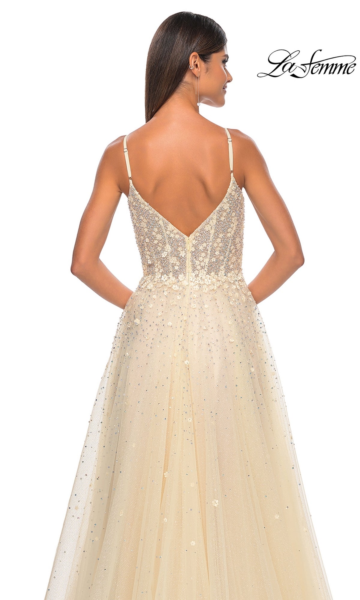 A woman poses with her back to the camera in the La Femme Embellished Long A-Line Prom Dress 32215, a sleeveless, sparkling light beige formal gown featuring a deep V-back. The La Femme logo is displayed in the top right corner.